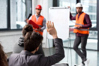 selective focus of man raising hand near handsome firemen in helmets standing near white board  clipart