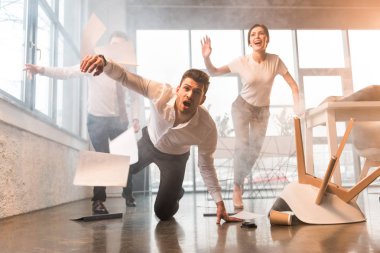 scared businessman falling on floor while running and screaming near coworkers in office with smoke clipart