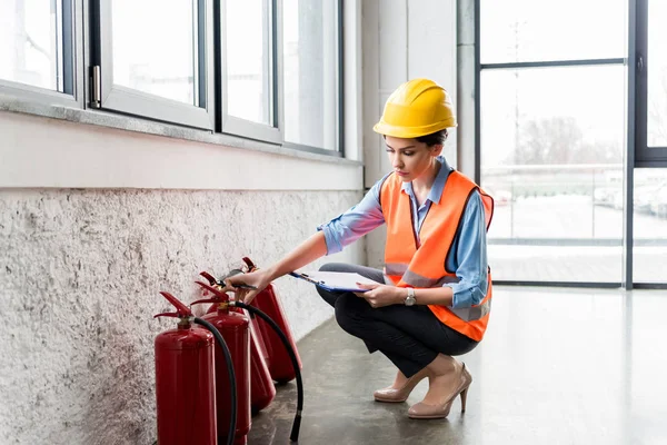 Aantrekkelijke Brandweerman Helm Klembord Pen Houden Terwijl Controle Van Brandblussers — Stockfoto