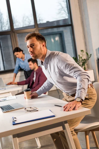 Bonito Aterrorizado Homem Segurando Copo Papel Perto Colegas Trabalho Escritório — Fotografia de Stock