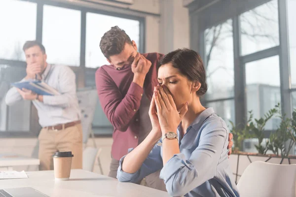 businesswoman holding nose near scared colleagues in office with smoke