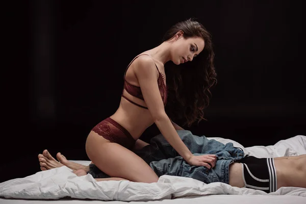 Atraente Jovem Mulher Sexy Lingerie Despindo Homem Cama Isolado Preto — Fotografia de Stock