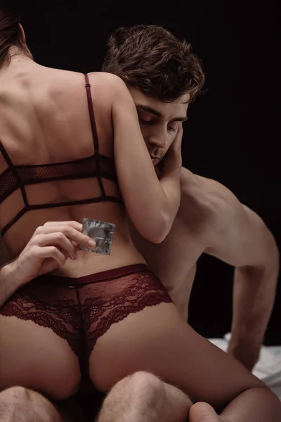 Baksidan Kvinnan Sexiga Underkläder Sitter Ovanpå Mannen Håller Kondom Isolerade — Stockfoto