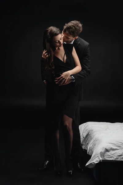 热情的年轻夫妇在正式穿接吻孤立的黑色 — 图库照片