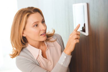 güzel sarışın kadın akıllı ev kontrol panelini kullanarak