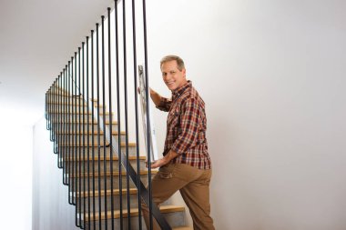smiling handsome man going upstairs and carrying picture  clipart