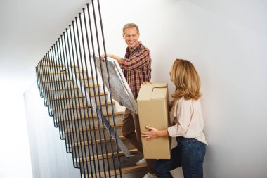 woman with cardboard box and man with picture going upstairs clipart