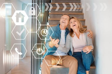 inspired smiling couple sitting on stairs at new home, smart home concept clipart