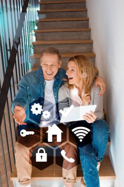 heyecanlı çift merdivenlerde oturan ve dijital tablet, akıllı ev concept kullanma