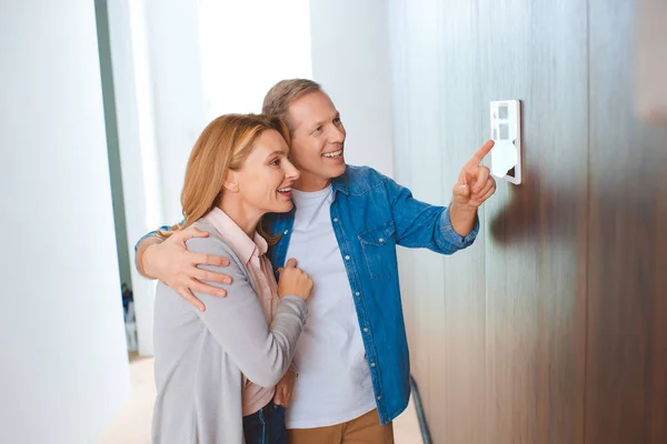 Homem Feliz Apontando Para Painel Controle Inteligente Casa Enquanto Abraçando — Fotografia de Stock