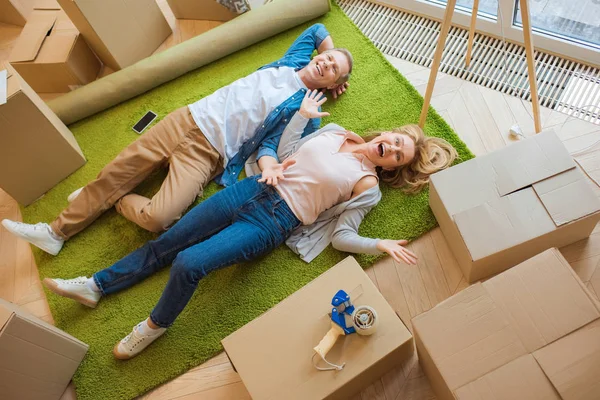 Feliz Pareja Acostada Suelo Sobre Una Alfombra Verde Rodeada Cajas —  Fotos de Stock