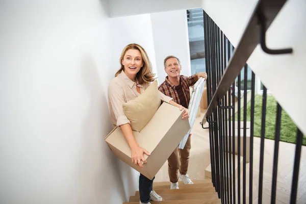 Cheerful Couple Carrying Things Upstairs Looking Camera — Stock Photo, Image