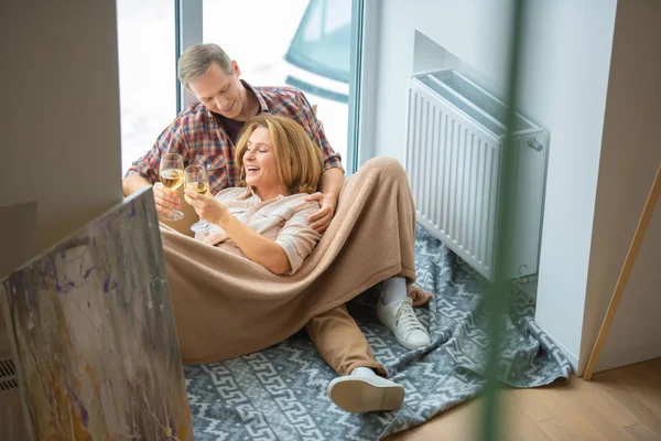 Pasangan Bahagia Mendentingkan Gelas Sambil Beristirahat Lantai Dengan Jendela Besar — Stok Foto