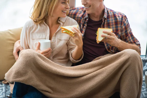 Casal Feliz Comendo Sanduíches Olhando Para Outro Enquanto Sentado Sob — Fotografia de Stock