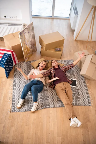 overhead view of happy excited couple laying on floor at new home