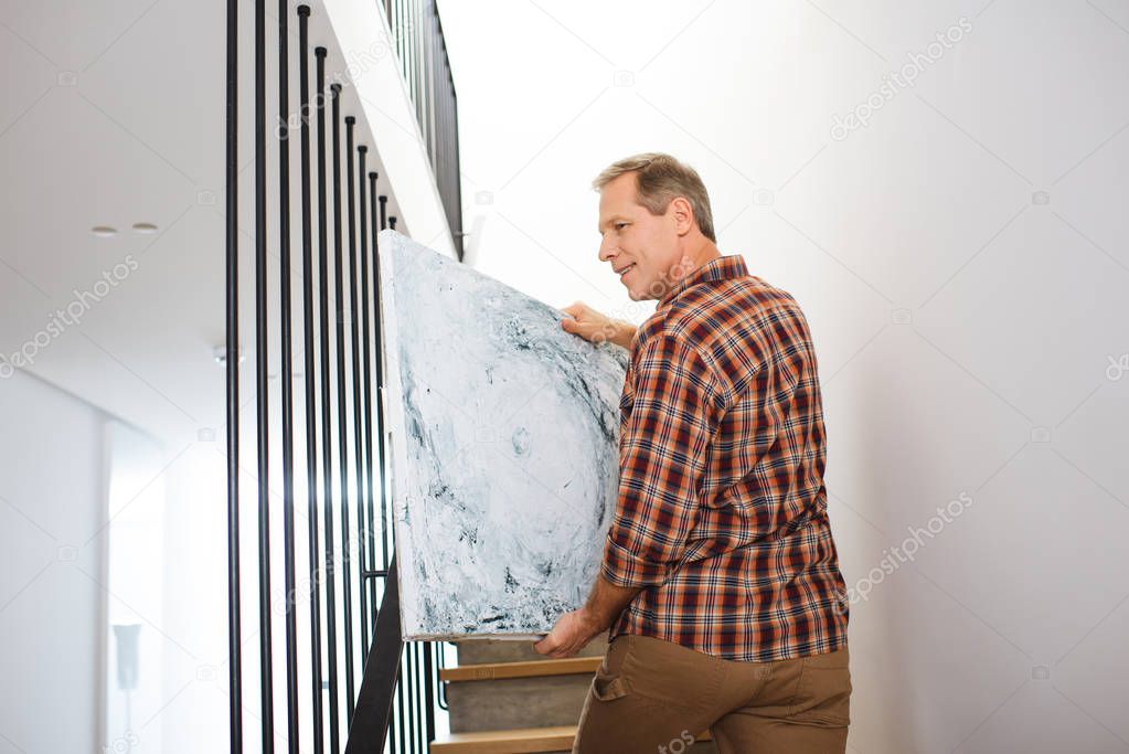handsome man going upstairs and carrying picture