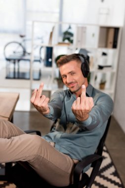 seçici odak neşeli adam orta parmak müzik dinleme sırasında kulaklık gösterilen 