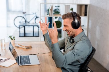 kulaklıklar müzik dinleme ve laptop ofiste rock işaret gösteren süre seyir mutlu işadamı