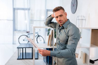 ayakta ve modern ofiste gazete tutan yakışıklı adam 