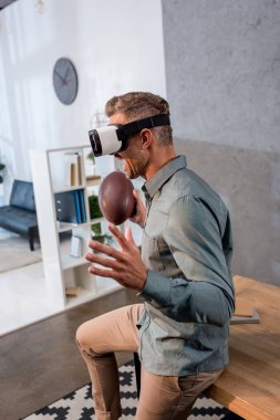 Amerikan futbolu tutarken sanal gerçeklik kulaklık giyen heyecanlı iş adamı 