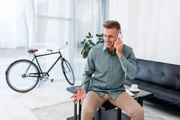 Hombre Negocios Emocional Hablando Teléfono Inteligente Mientras Está Sentado Mesa — Foto de Stock