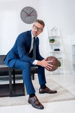 Basketbol kahve masada otururken elinde tutan takım elbiseli yakışıklı işadamı