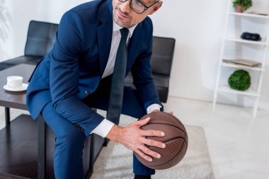 işadamı gözlük ve basketbol kahve masada otururken elinde tutan takım elbise görünümünü kırpılmış