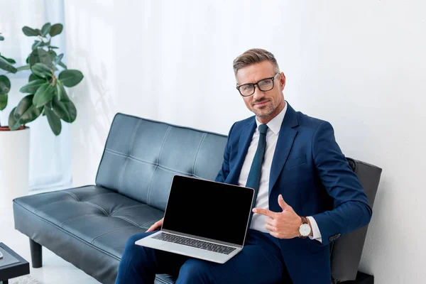 Empresário Alegre Terno Sentado Sofá Apontando Com Dedo Para Laptop — Fotografia de Stock