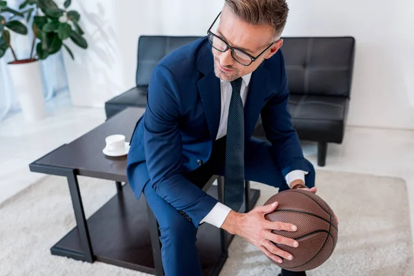 yakışıklı işadamı gözlük ve basketbol kahve masada otururken elinde tutan takım elbise