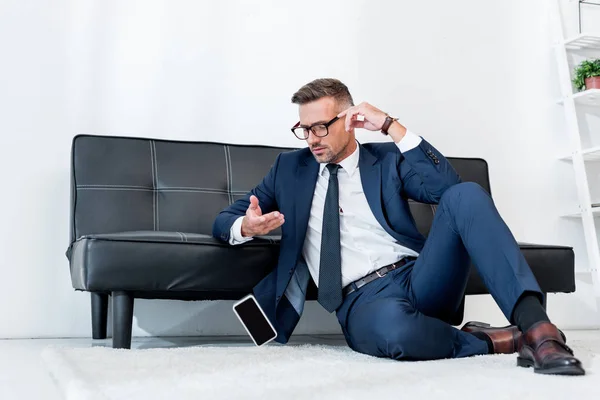 Schöner Geschäftsmann Anzug Sitzt Auf Teppich Neben Sofa Und Schaut — Stockfoto