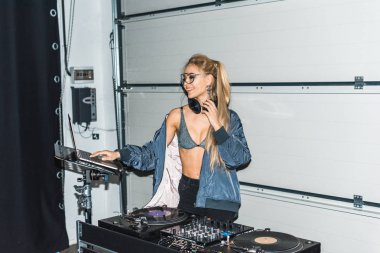 neşeli dj kadın gözlük ve dizüstü bilgisayar kullanarak kulaklık