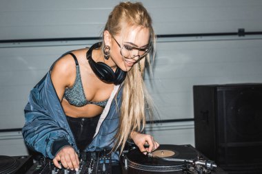 DJ mixer ve vinil kayıt yanında duran mutlu sarışın dj kadın