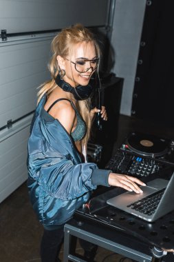 neşeli dj kadın şişe tutan el laptop kullanırken gözlük
