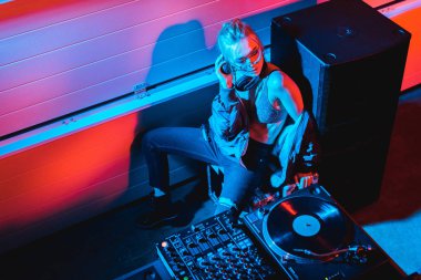 overhead view of dj girl with blonde hair sitting near dj equipment in nightclub clipart