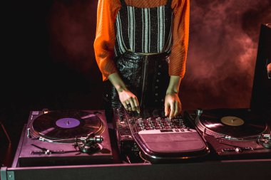 cropped view of dj girl touching dj equipment in nightclub with smoke clipart