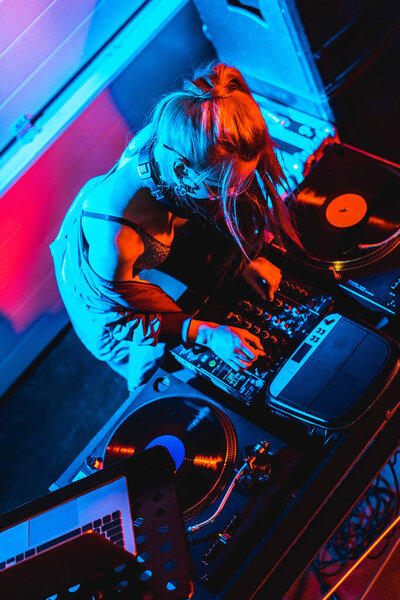 overhead view of blonde dj girl touching dj mixer in nightclub