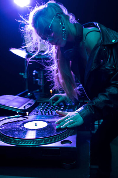 beautiful blonde dj girl touching vinyl record in nightclub 