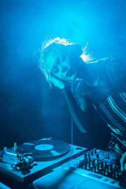 güzel dj kız dinleme müzik kulaklık duran duman ile gece kulübünde Kapalı gözlerle 