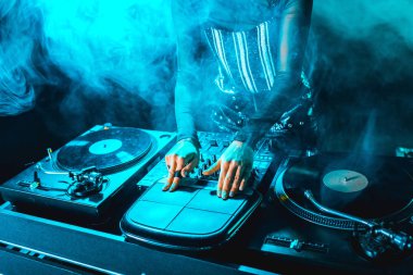 cropped view of dj woman using dj equipment in nightclub with smoke clipart