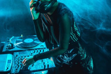 dj kadın dumanlı gece kulübünde dj mikser kullanarak kırpılmış görünümünü 
