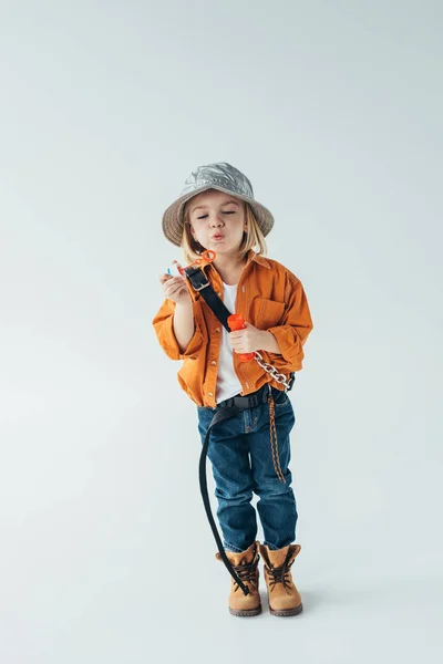ジーンズと灰色の背景にシャボン玉を吹いているオレンジ色のシャツでかわいい子供 — ストック写真
