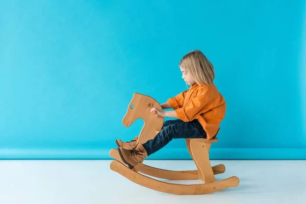 Side View Blonde Cute Kid Riding Rocking Horse Blue Background — Stock Photo, Image