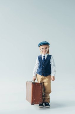 retro yelek ve bavul holding ve kameraya bakarak kap mutlu çocuk 