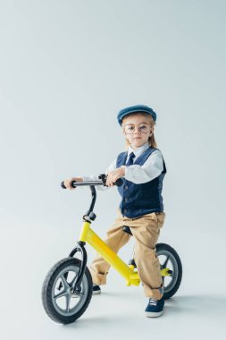 retro yelek ve Bisiklete binmek ve gri arka plan üzerinde kameraya bakarak kap ciddi çocuk