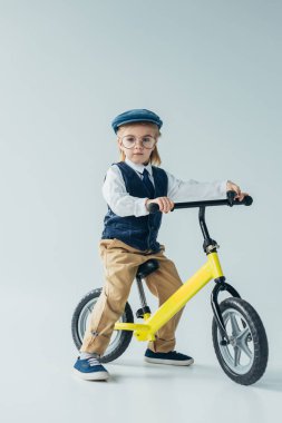 retro yelek ve Bisiklete binmek ve gri arka plan üzerinde kameraya bakarak kap evlat
