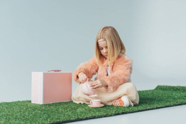  gri izole pembe oyuncak yemekleri ile oynarken çapraz ayaklı oturan çocuk