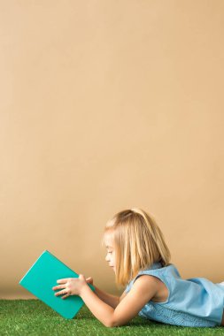  çim halı üzerinde yalan ve bej renkli arka plan üzerinde kitap okuma ufaklık 