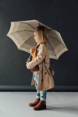 Çocuk yağmurluk ve şemsiye siyah arka planda tutan kot pantolon yan görünüm