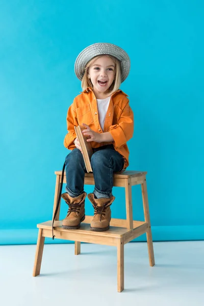 Улыбающийся Ребенок Джинсах Оранжевой Рубашке Сидит Лестнице Держит Книгу — стоковое фото