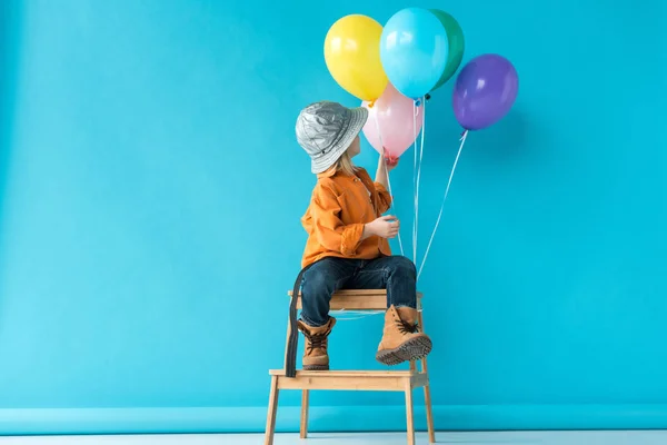 Lindo Niño Jeans Camisa Naranja Sentado Escaleras Mirando Globos — Foto de Stock